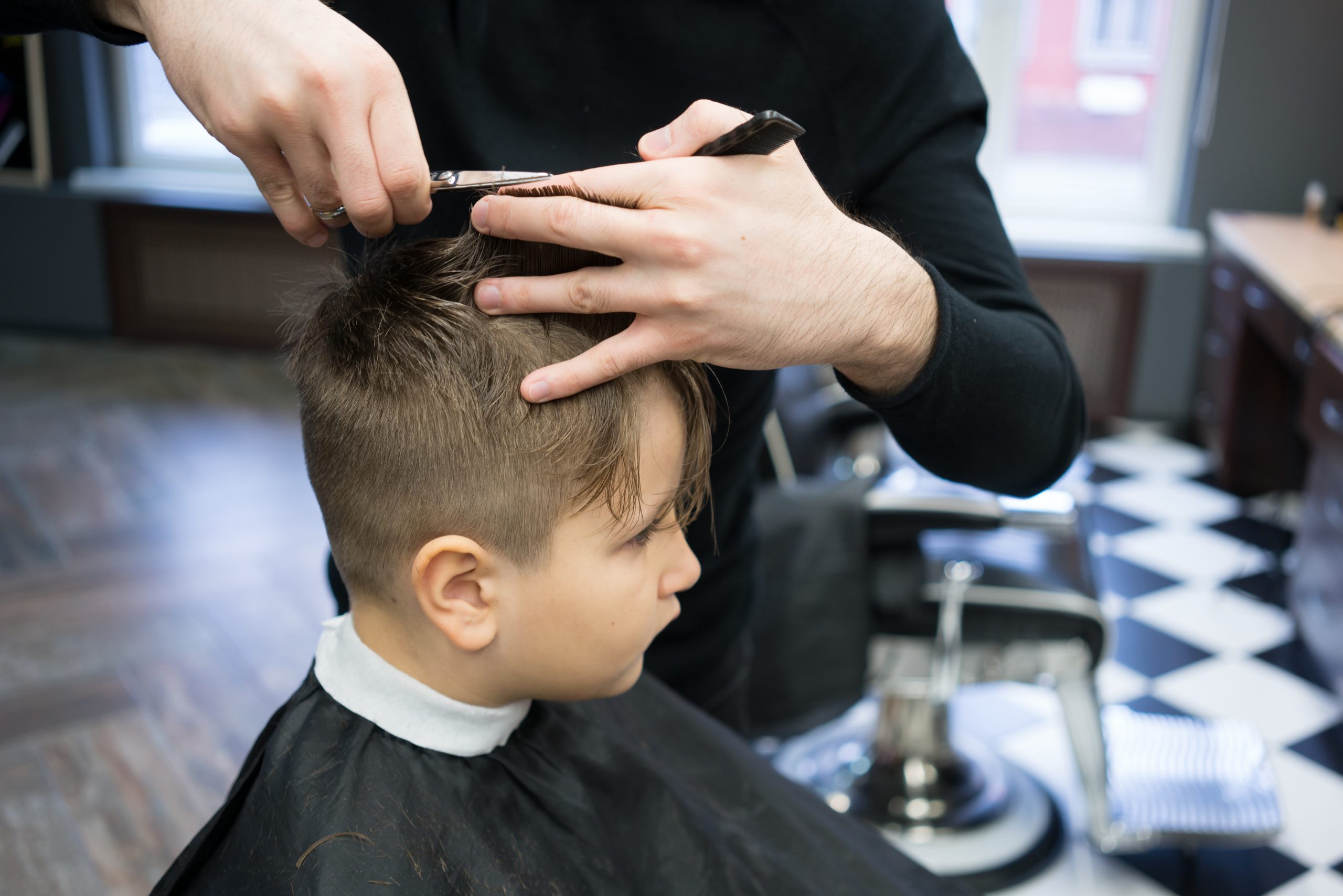 Friseur Augustin in Gelsenkirchen-Schneiden einer Kinderfrisur mit Schere an einem Jungen